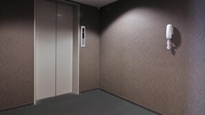 Un pasillo con una puerta, un teléfono en la pared y una pared con textura.