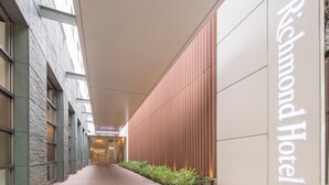 A corridor leading to the Richmond Hotel with a modern facade, glass doors, and a sign indicating the hotel name. - Richmond Hotel Kumamoto Shinshigai (Kumamoto)