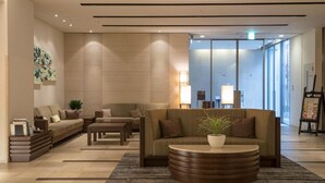 A modern lobby with sofas, a coffee table, and a reception desk. - Richmond Hotel Kumamoto Shinshigai (Kumamoto)