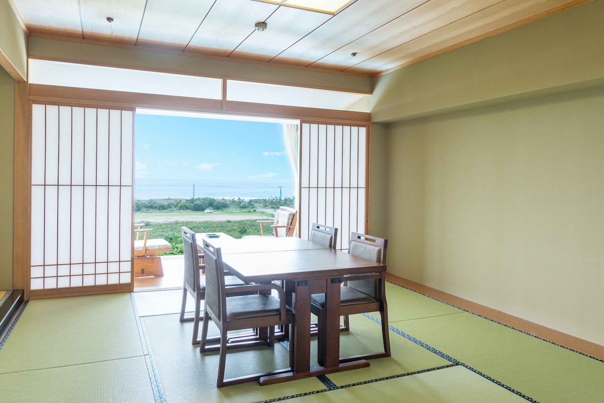 Une pièce de style japonais traditionnel, avec un sol recouvert de tatamis, une table basse et des portes coulissantes.