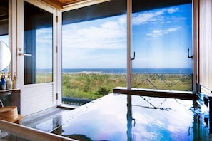 Habitación con un ventanal grande con vistas a un paisaje, una bañera y un banco de madera.