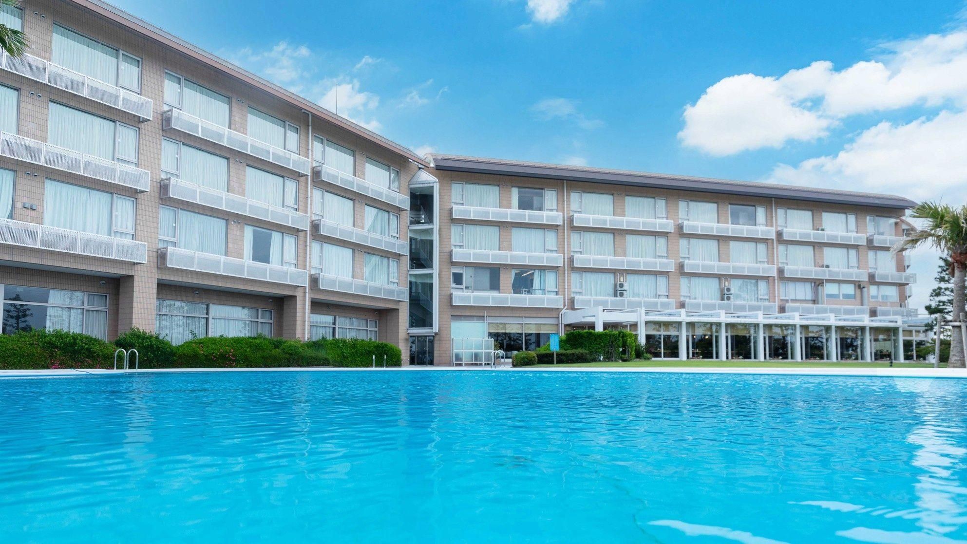 Un hotel con varios pisos, balcones y una piscina.