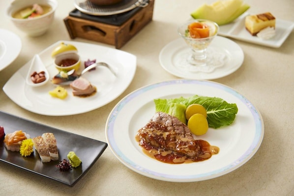 A variety of dishes on a table, including a plate with meat and vegetables, a bowl of soup, and several small plates with different foods. - Hotel Ichinomiya Seaside Otsuka (Ichinomiya)