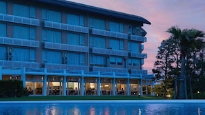 A multi-story hotel with balconies, a pool, and outdoor seating areas. - Hotel Ichinomiya Seaside Otsuka (Ichinomiya)