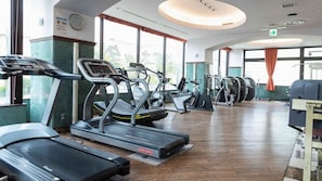 Un gimnasio con cintas de correr, elípticas y un banco para pesas.