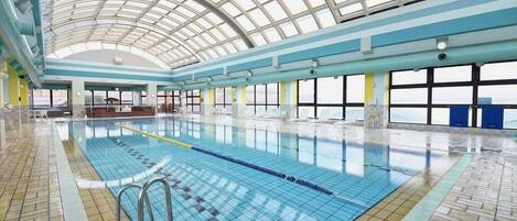 An indoor swimming pool with a high ceiling and large windows.