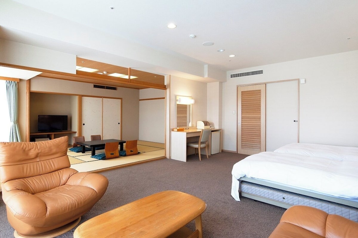 Une chambre d’hôtel comprenant un lit, un bureau, une chaise, un canapé et un téléviseur.