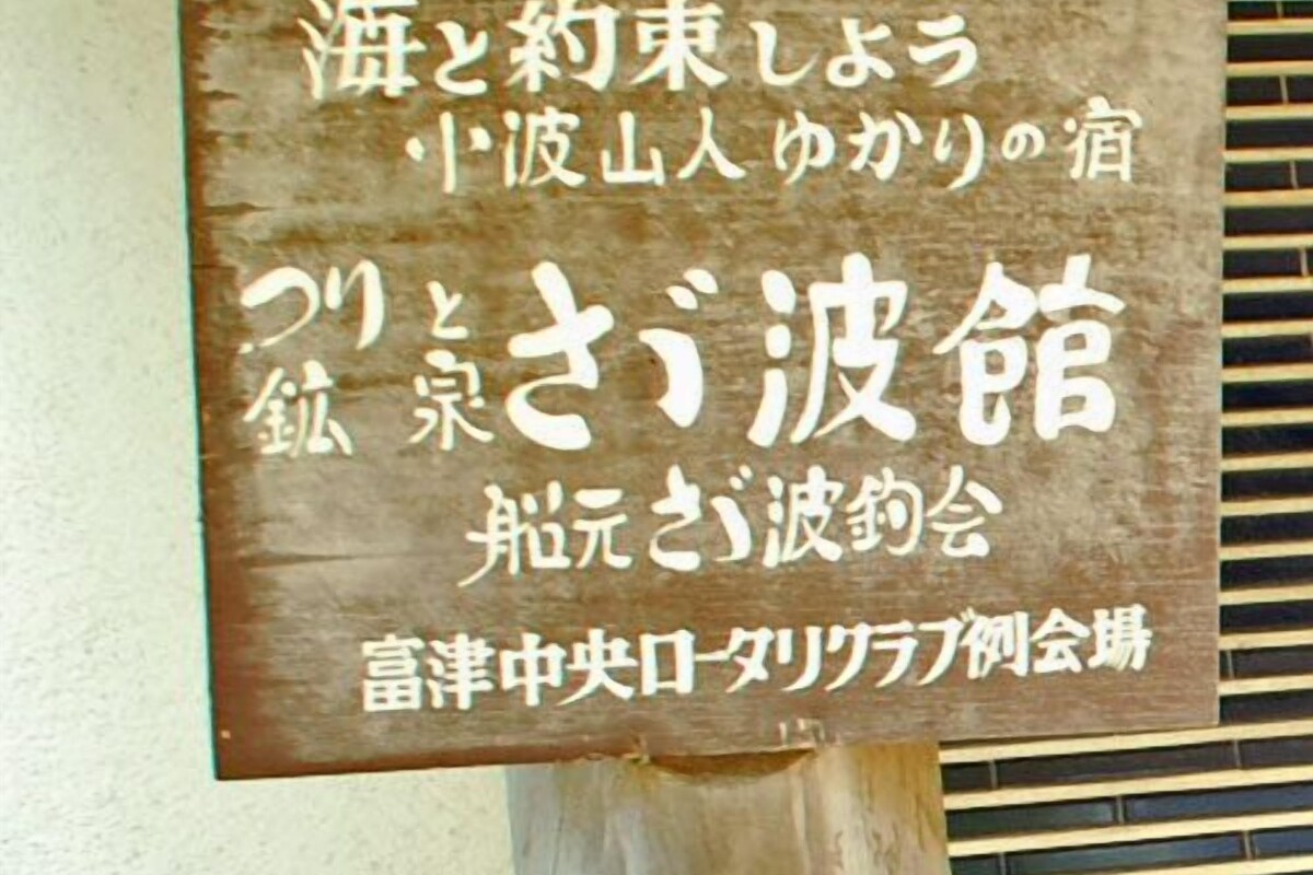 A wooden sign with Japanese text, likely indicating the name and type of a building or establishment.
