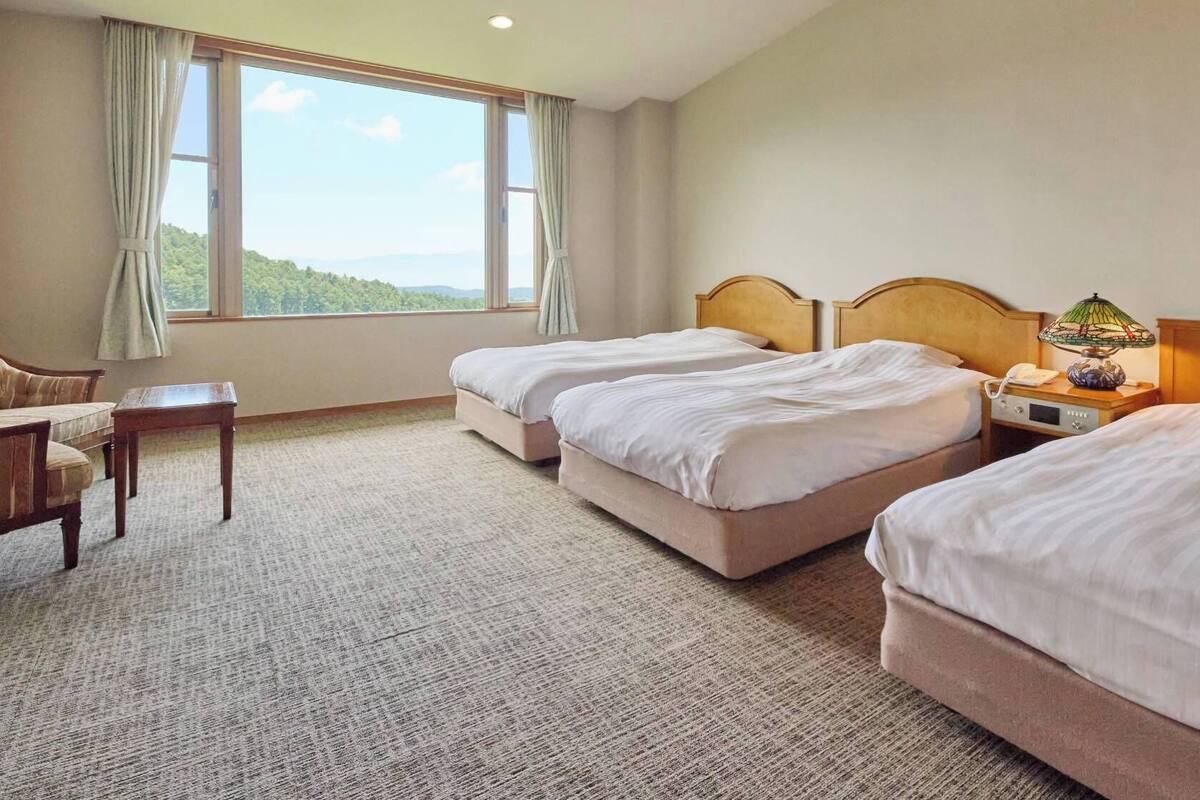 Ein Hotelzimmer mit zwei Betten, einem Schreibtisch und Blick ins Freie.
