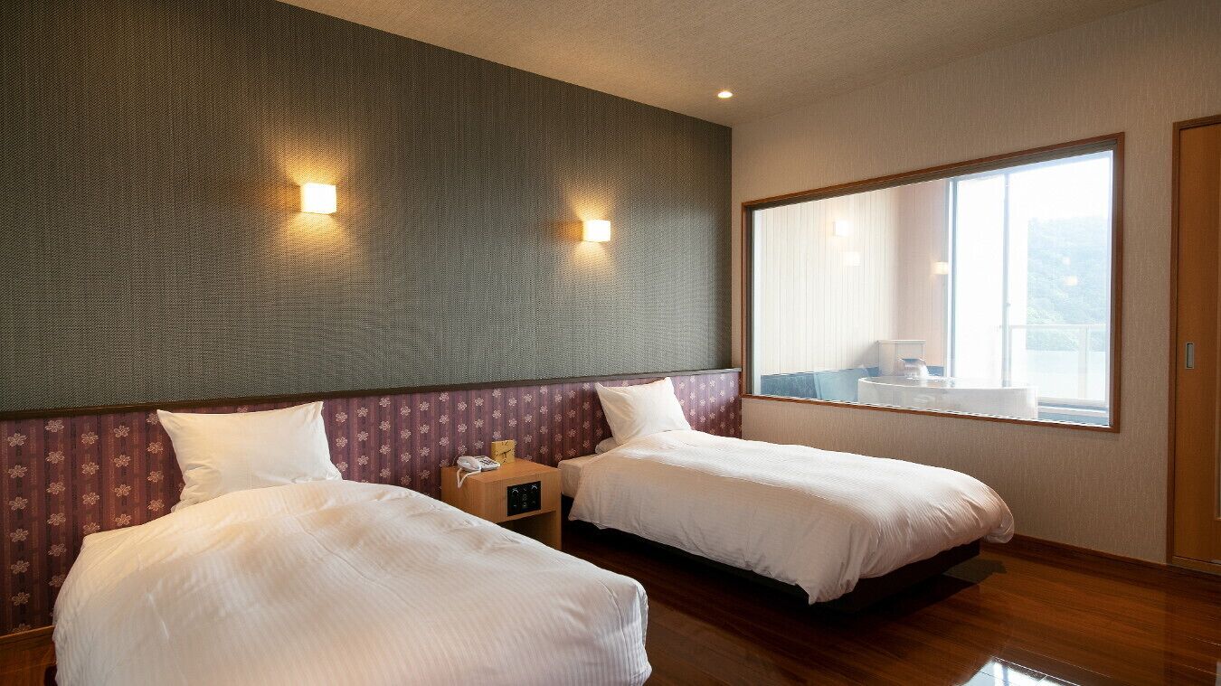 Ein Hotelzimmer mit zwei Betten, einem großen Fenster und Blick nach draußen.