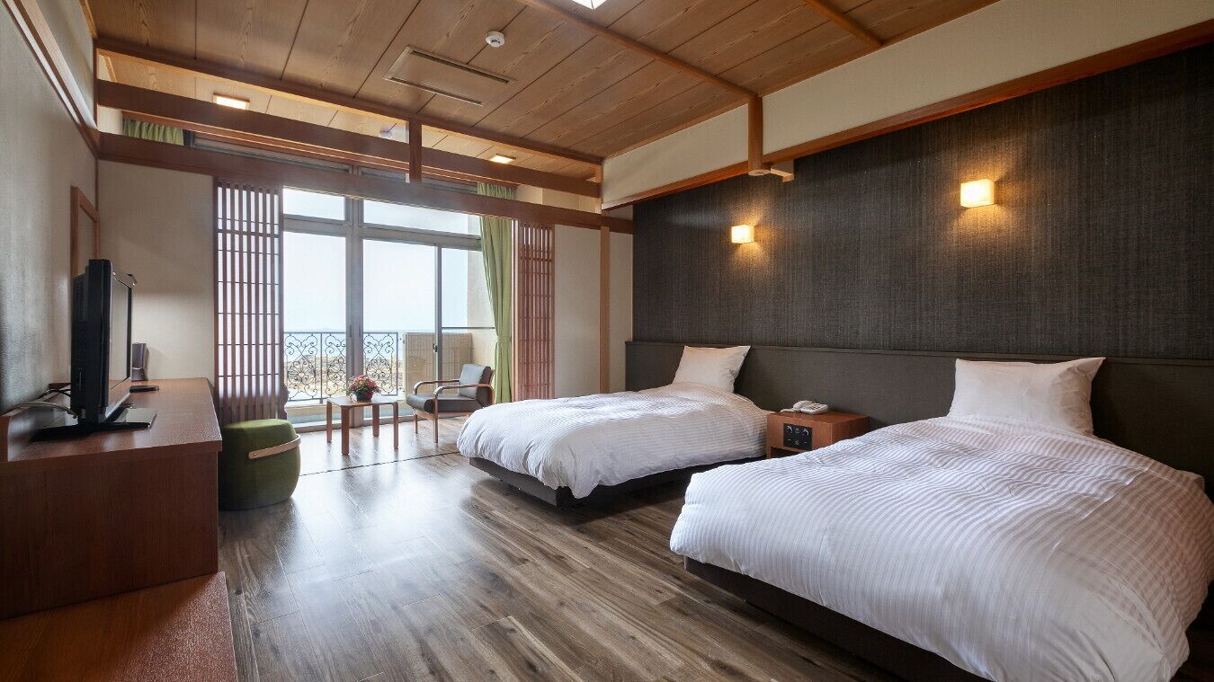 Ein Hotelzimmer mit zwei Betten, einem Schreibtisch mit Fernseher und einem Balkon mit Blick.