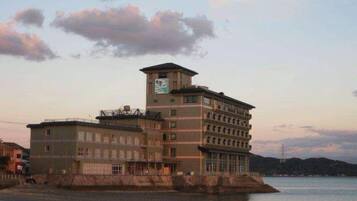 A multi-story hotel with a prominent tower, situated by a body of water.