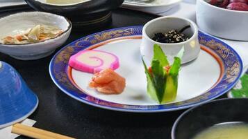 A variety of dishes on a tray, including sushi, a rolled item, and a bowl of soup.