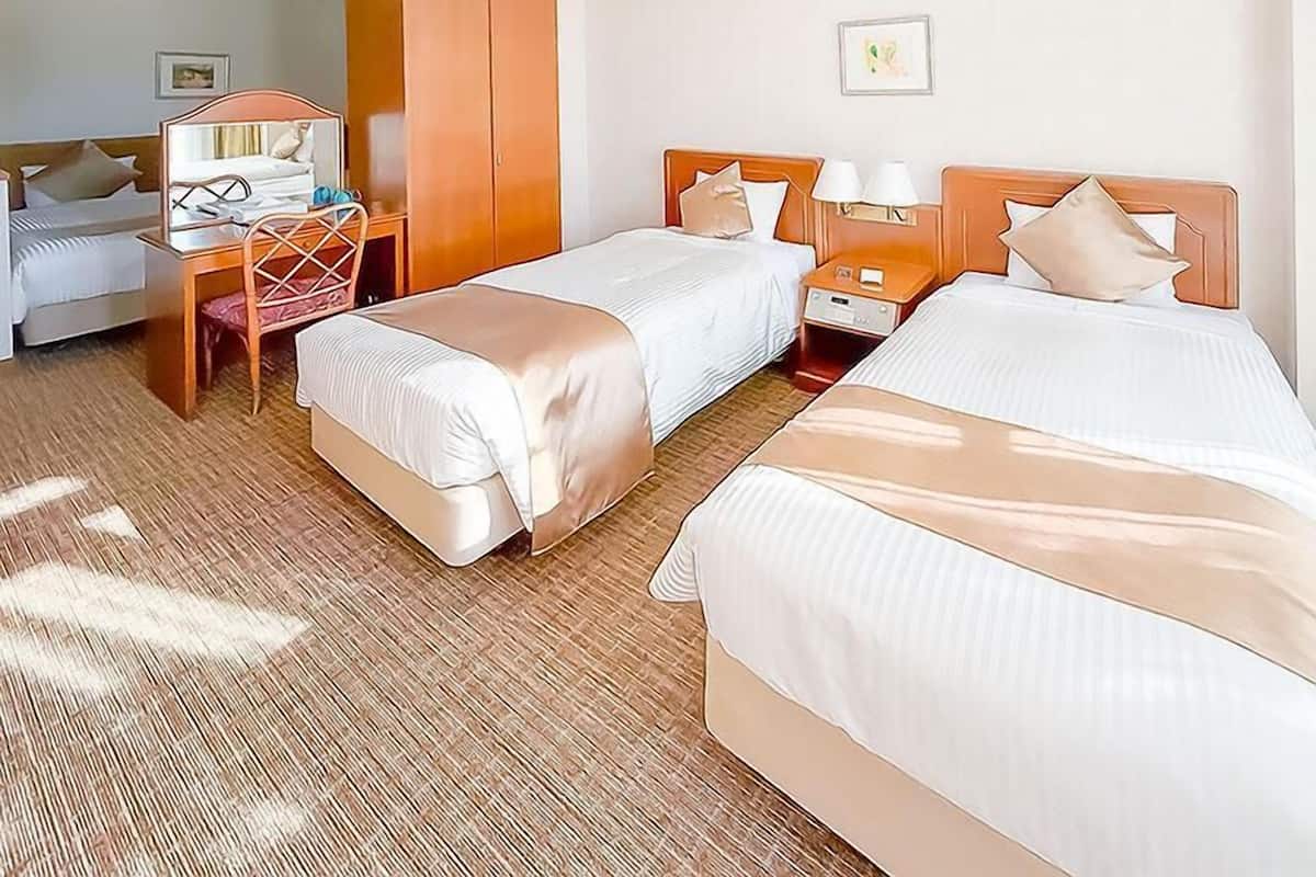 Ein Hotelzimmer mit zwei Betten, einem Schreibtisch und einem Stuhl.