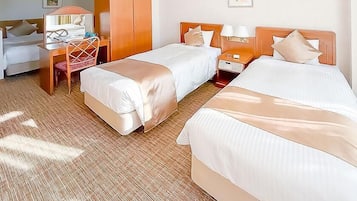 Quarto de hotel com duas camas, uma escrivaninha e uma cadeira.