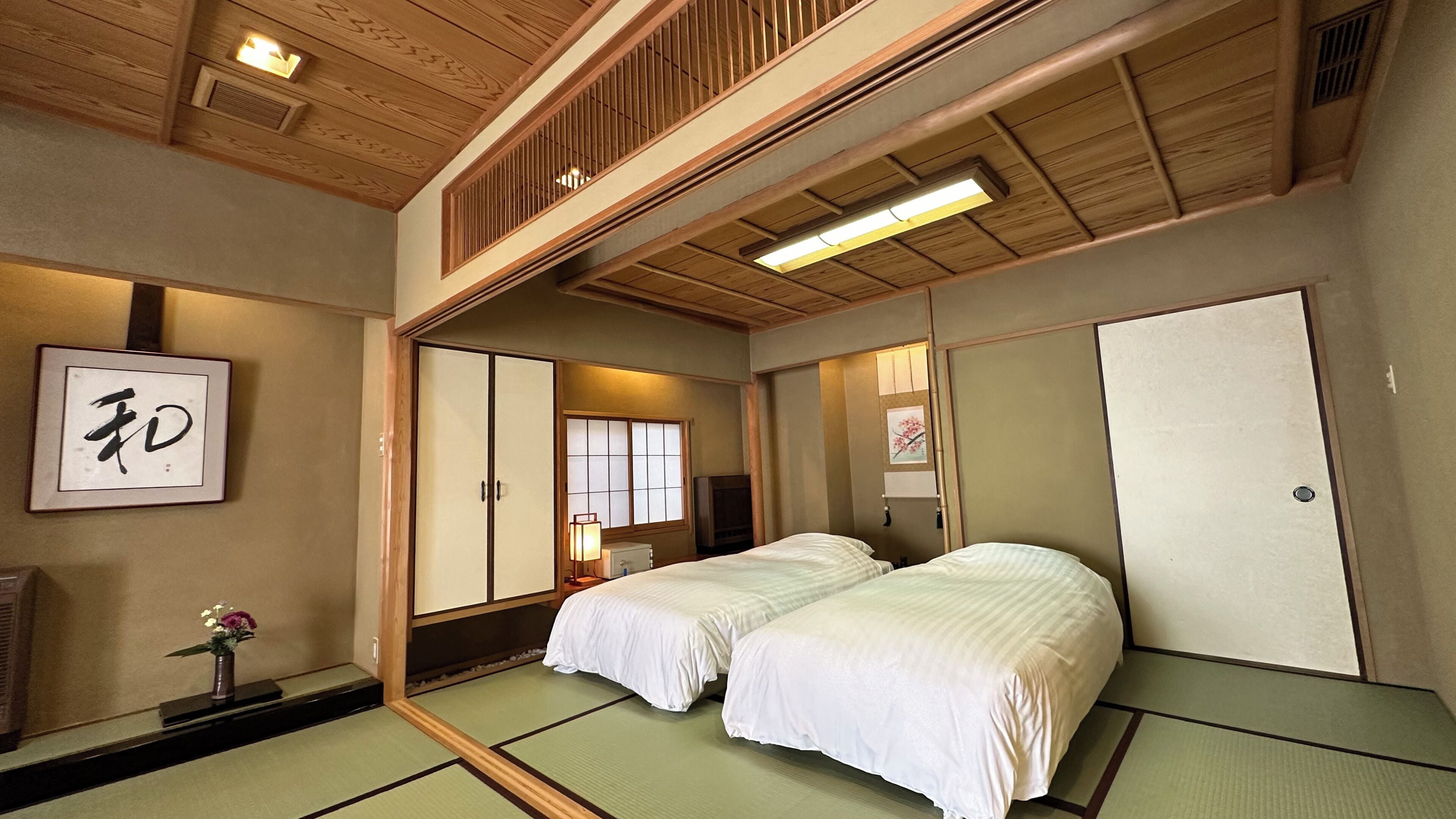 Una habitación japonesa tradicional con suelo de tatami, un futón, puertas correderas y un televisor.