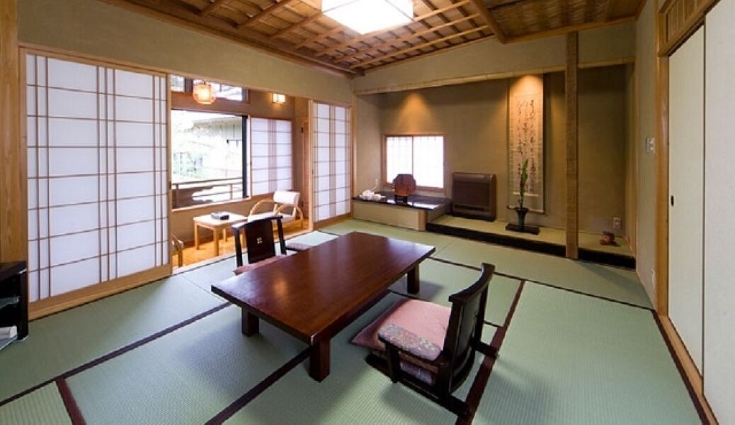Um quarto japonês tradicional com tatames, uma mesa de madeira baixa e portas deslizantes.