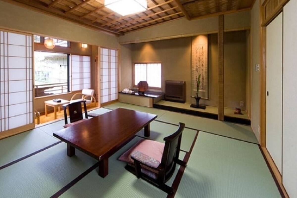 Una habitación japonesa tradicional con suelo de tatami, una mesa de madera baja y puertas correderas.