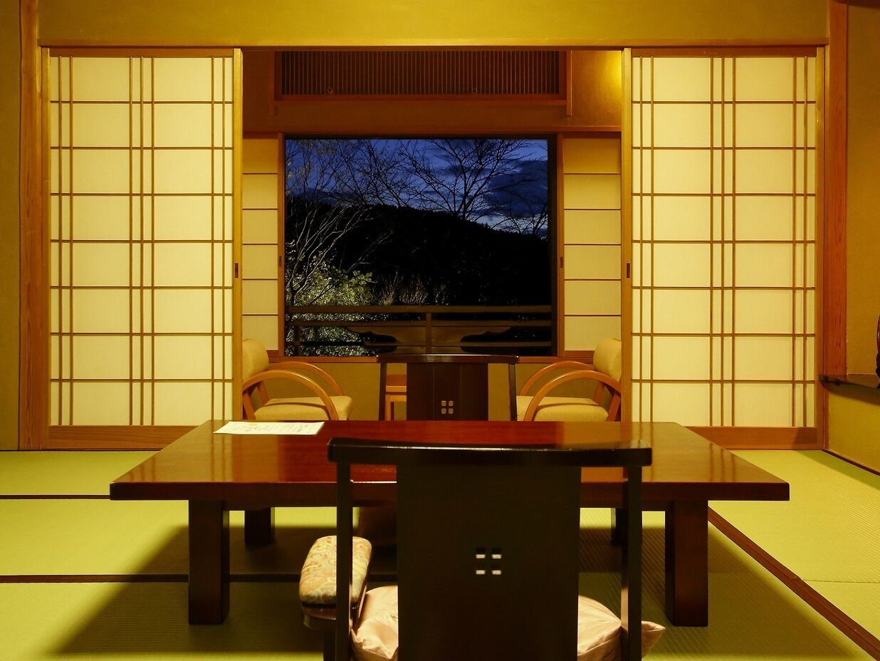 Um quarto japonês tradicional com tatames, uma mesa baixa e portas deslizantes.