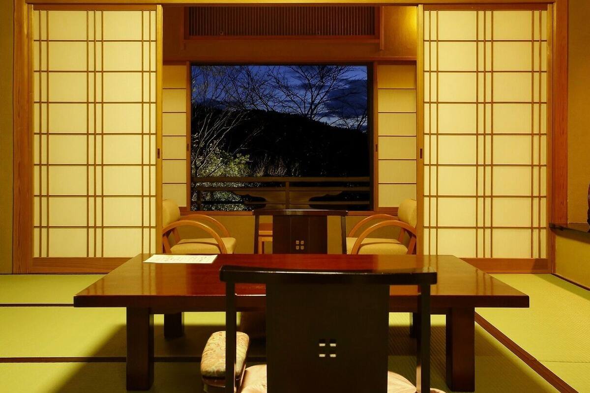 Una habitación japonesa tradicional con suelo de tatami, una mesa baja y puertas correderas.
