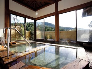 A hot spring bath with wooden steps, large windows, and a view of a forested landscape. - Takechiyo Kirishima Bettei (Kirishima)
