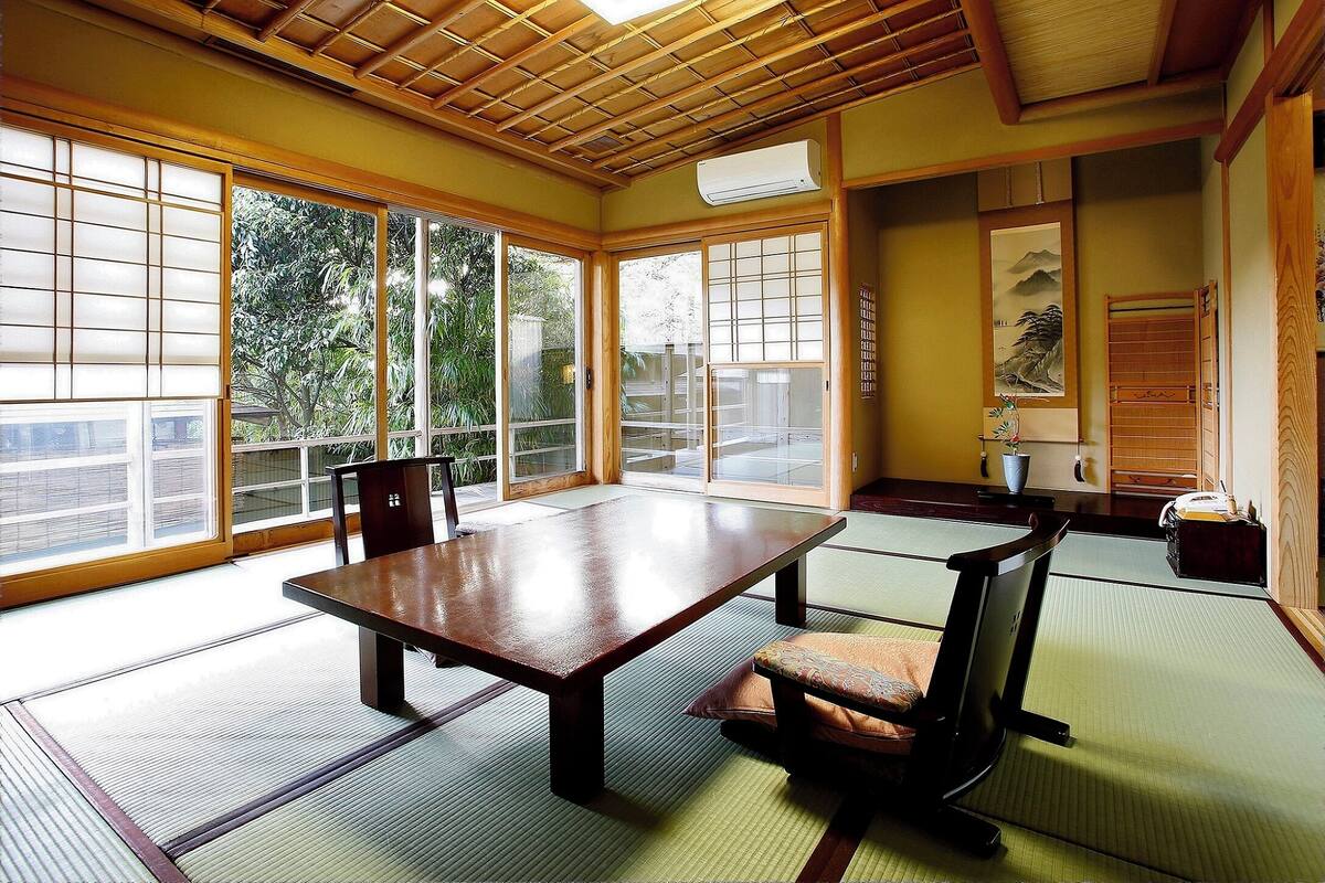 Una habitación japonesa tradicional con suelo de tatami, una mesa baja y puertas correderas.