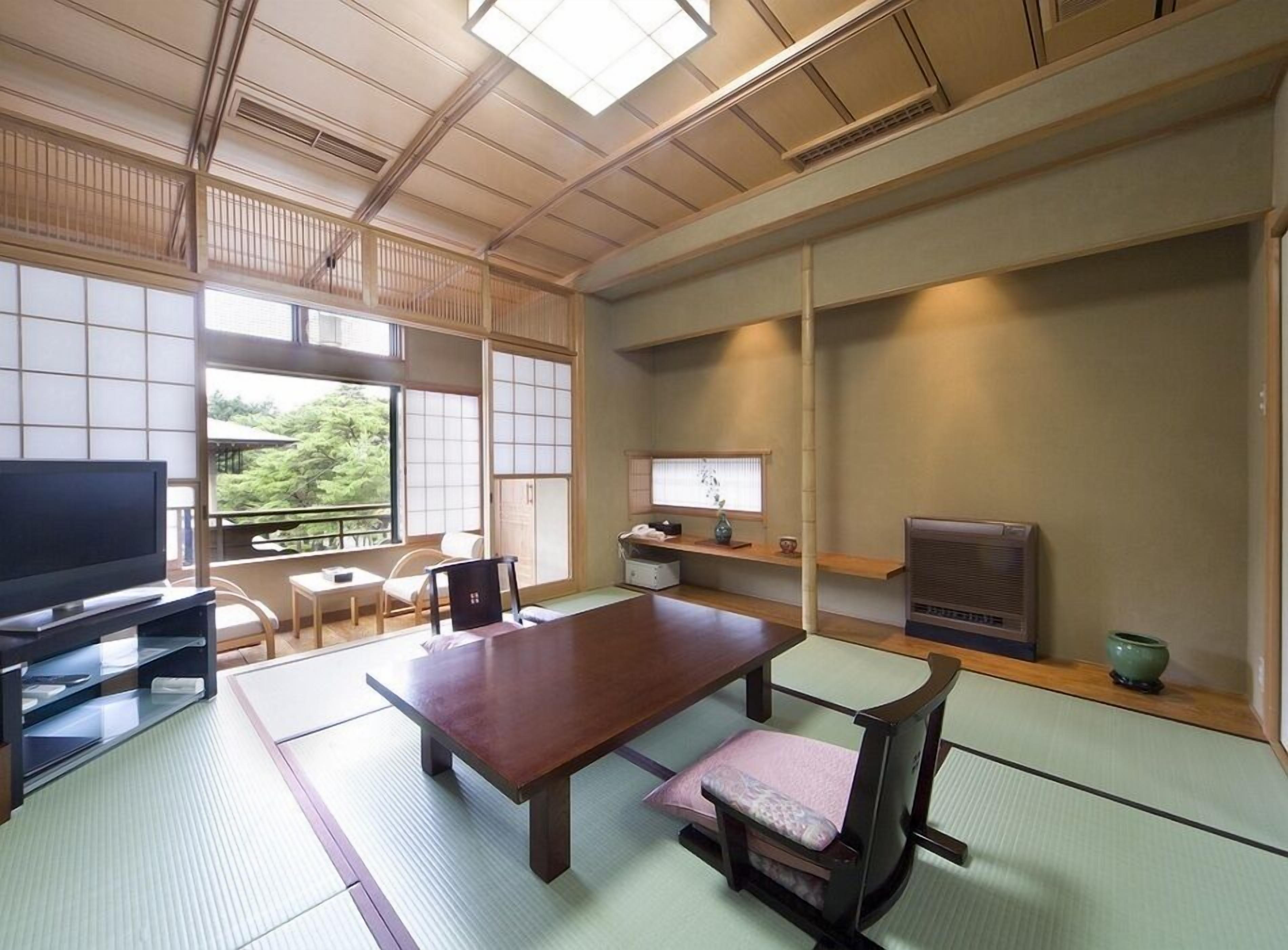 Um quarto japonês tradicional com tatames, uma mesa baixa, uma televisão e uma porta de correr.