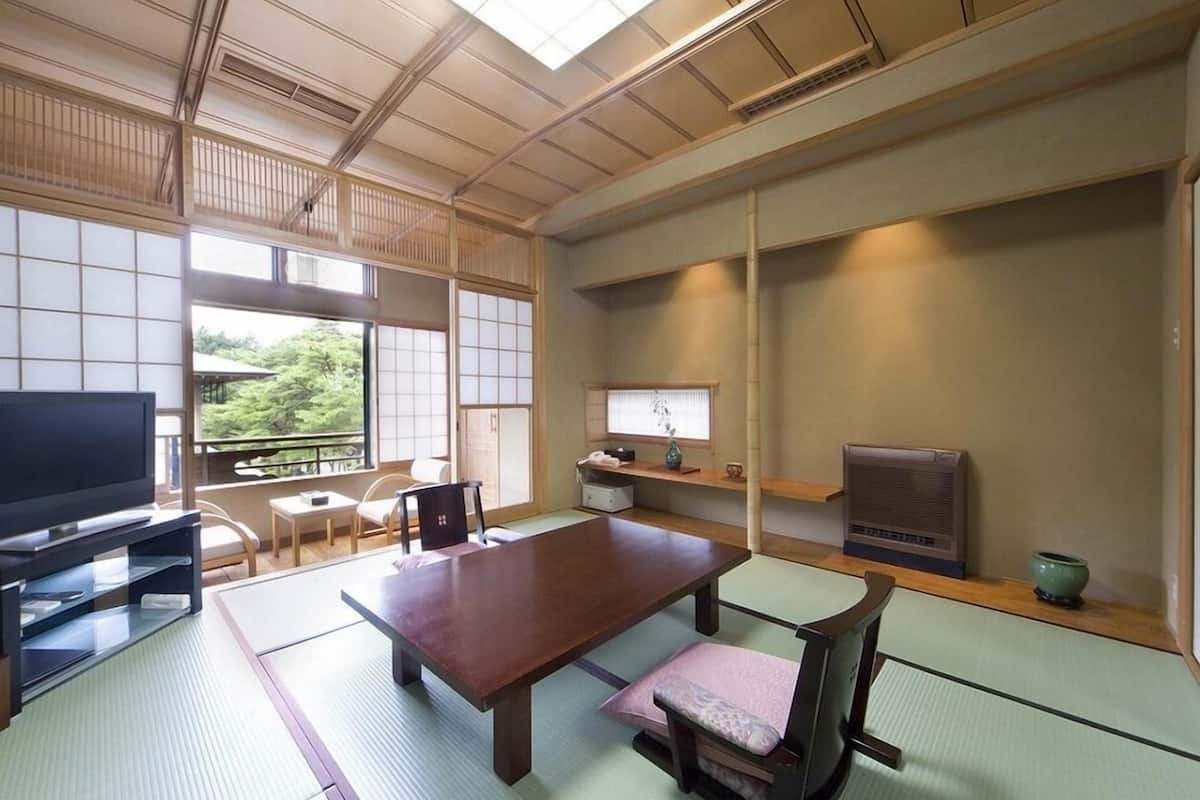 A traditional Japanese room with tatami flooring, a low table, a television, and a sliding door.