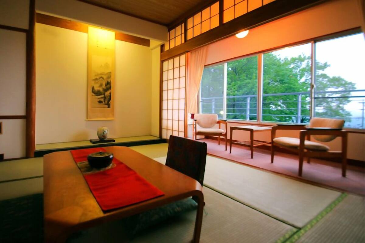 A traditional Japanese room with tatami flooring, a low table, and sliding doors.