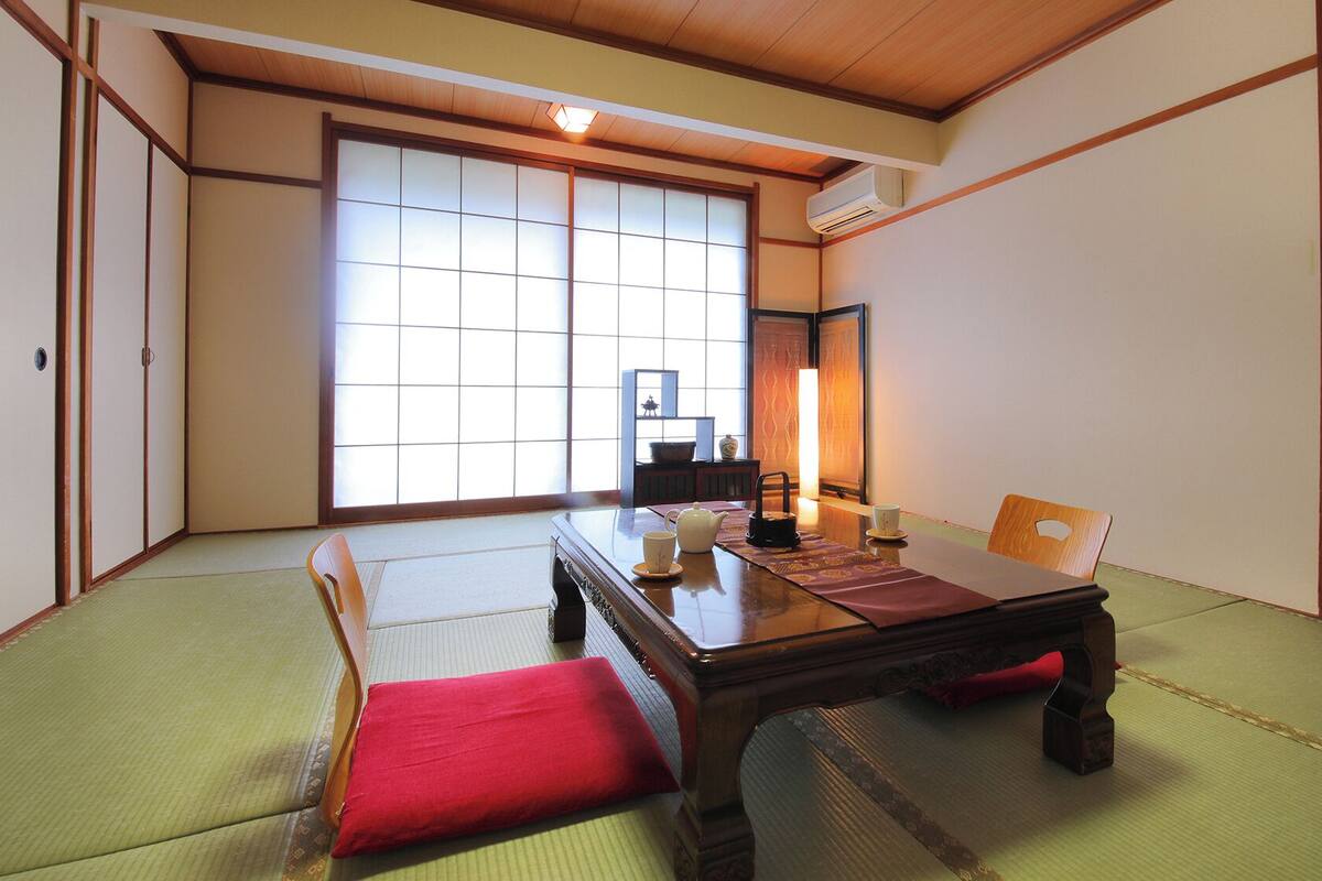 A traditional Japanese room with tatami flooring, a low wooden table, and sliding doors.