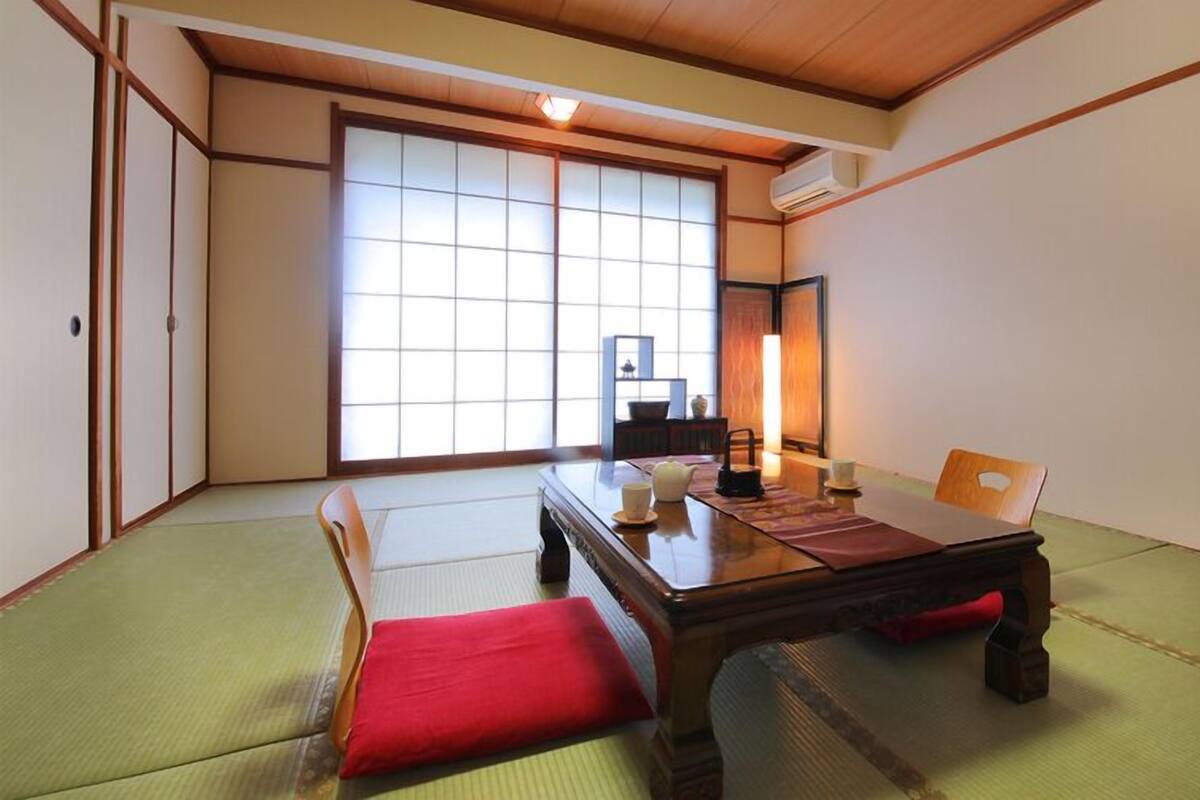 A tatami mat room with a low table, cushions, and sliding doors.