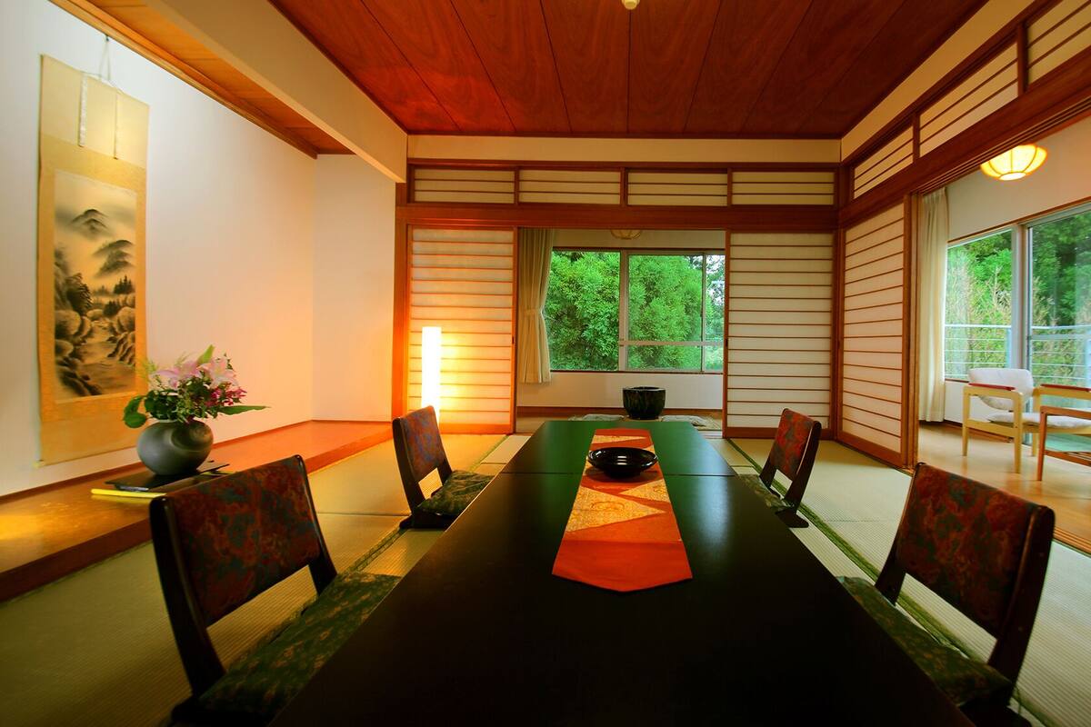 A traditional Japanese-style dining room with tatami mats, a low table, and shoji screens.