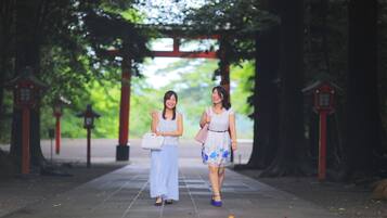 Twee personen lopen onder een traditionele boog in een parkachtige omgeving.