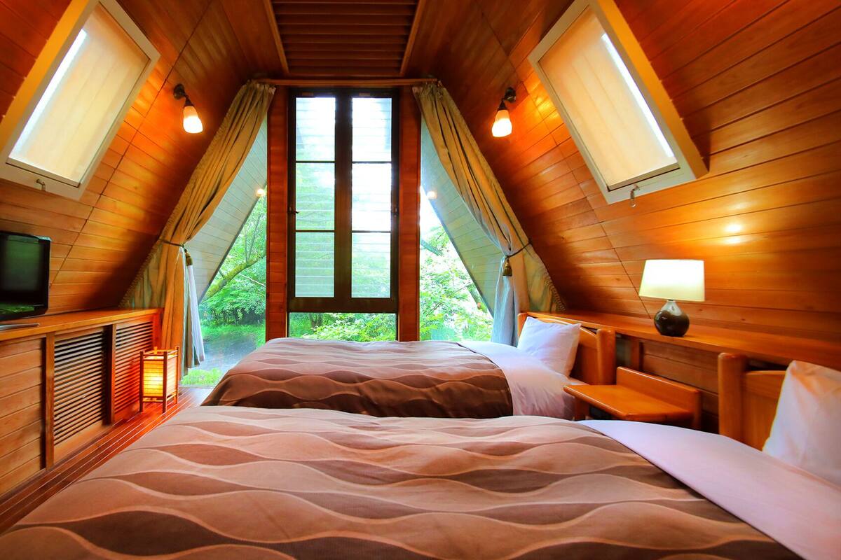 A bedroom with a bed, a television, a lamp, and a window with curtains.