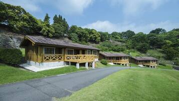 A row of wooden cabins with a stone wall and a paved path leading to them.