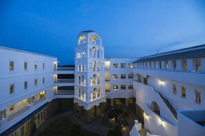 Un hotel de varios pisos con una torre central, balcones y un patio.