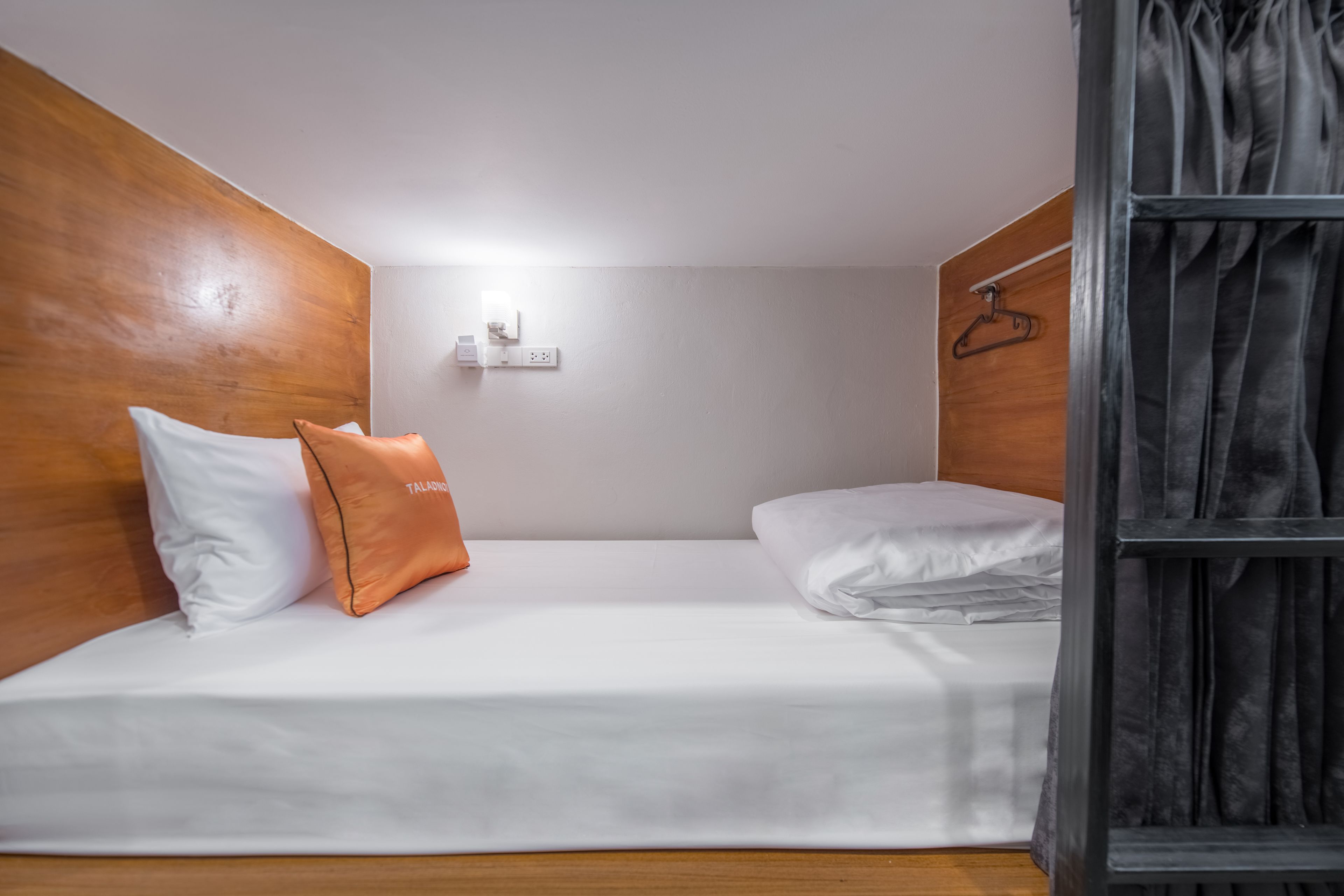 A small, single-bed room with wooden headboard and a hanging coat rack.
