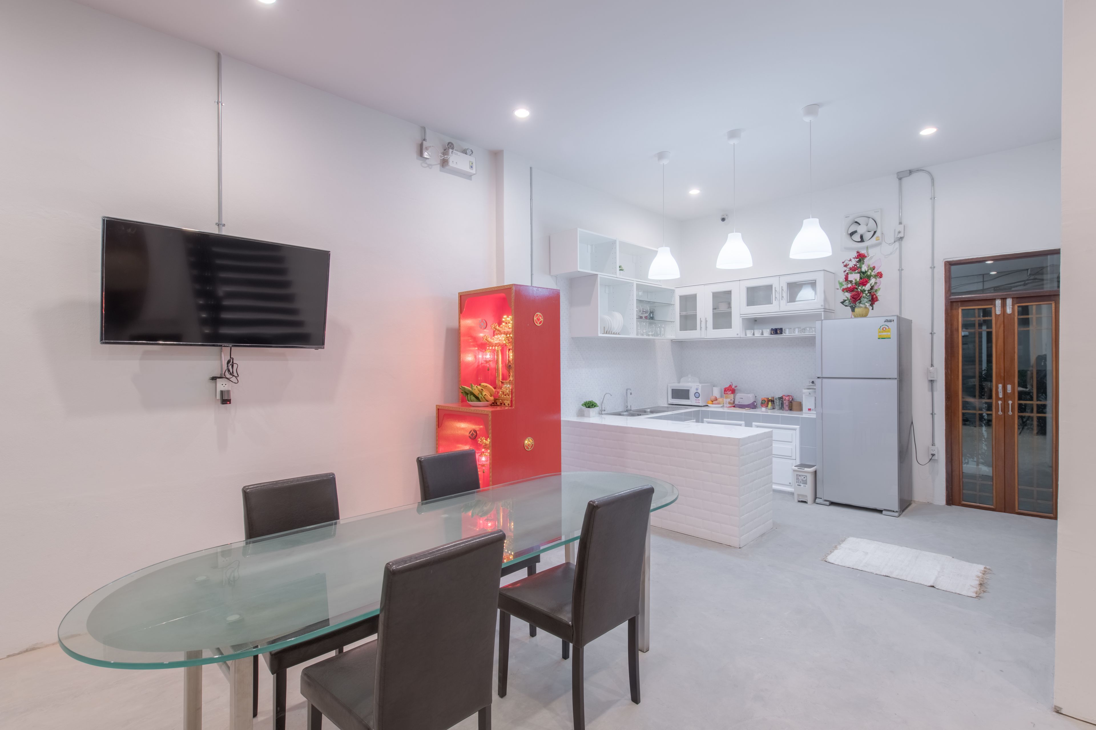 A modern kitchen with white cabinets, a central island, and a dining area with a glass table and chairs.