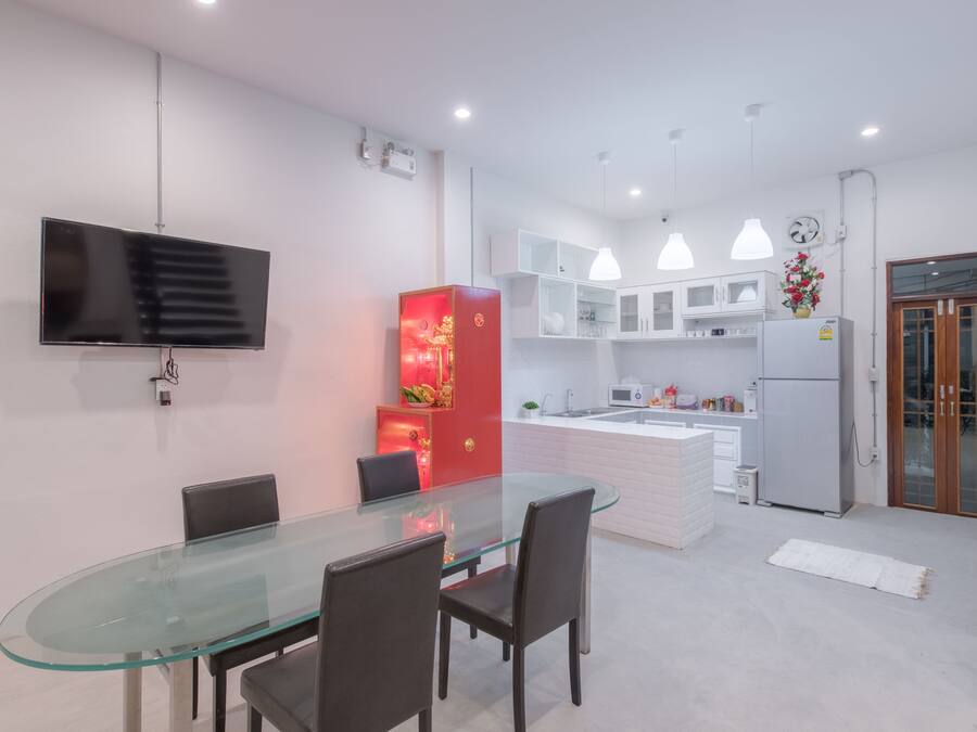 A modern kitchen with white cabinets, a central island, and a dining area with a glass table and chairs.