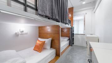Ein kleines Hotelzimmer mit Stockbetten, einem kleinen Schreibtisch und einem Fenster mit Vorhängen.