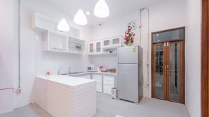A modern kitchen with white cabinetry, a central island, and pendant lighting. - Tiny Taladnoi Hostel (Bangkok)