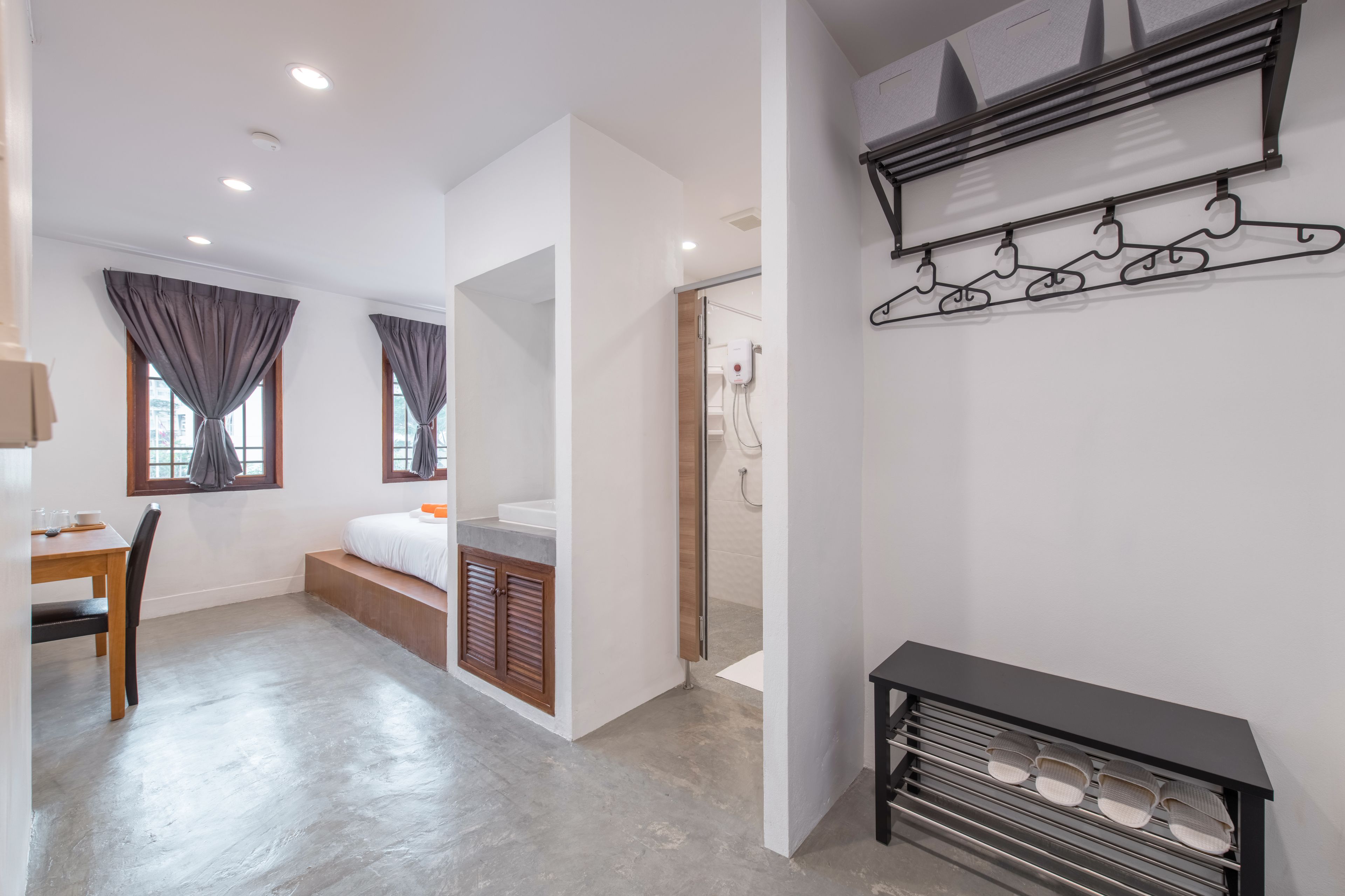 A modern hotel room with a bed, a desk, and a shower area.