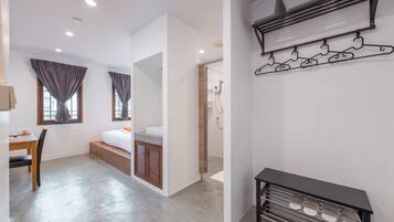 A modern hotel room with a bed, a desk, and a shower area.