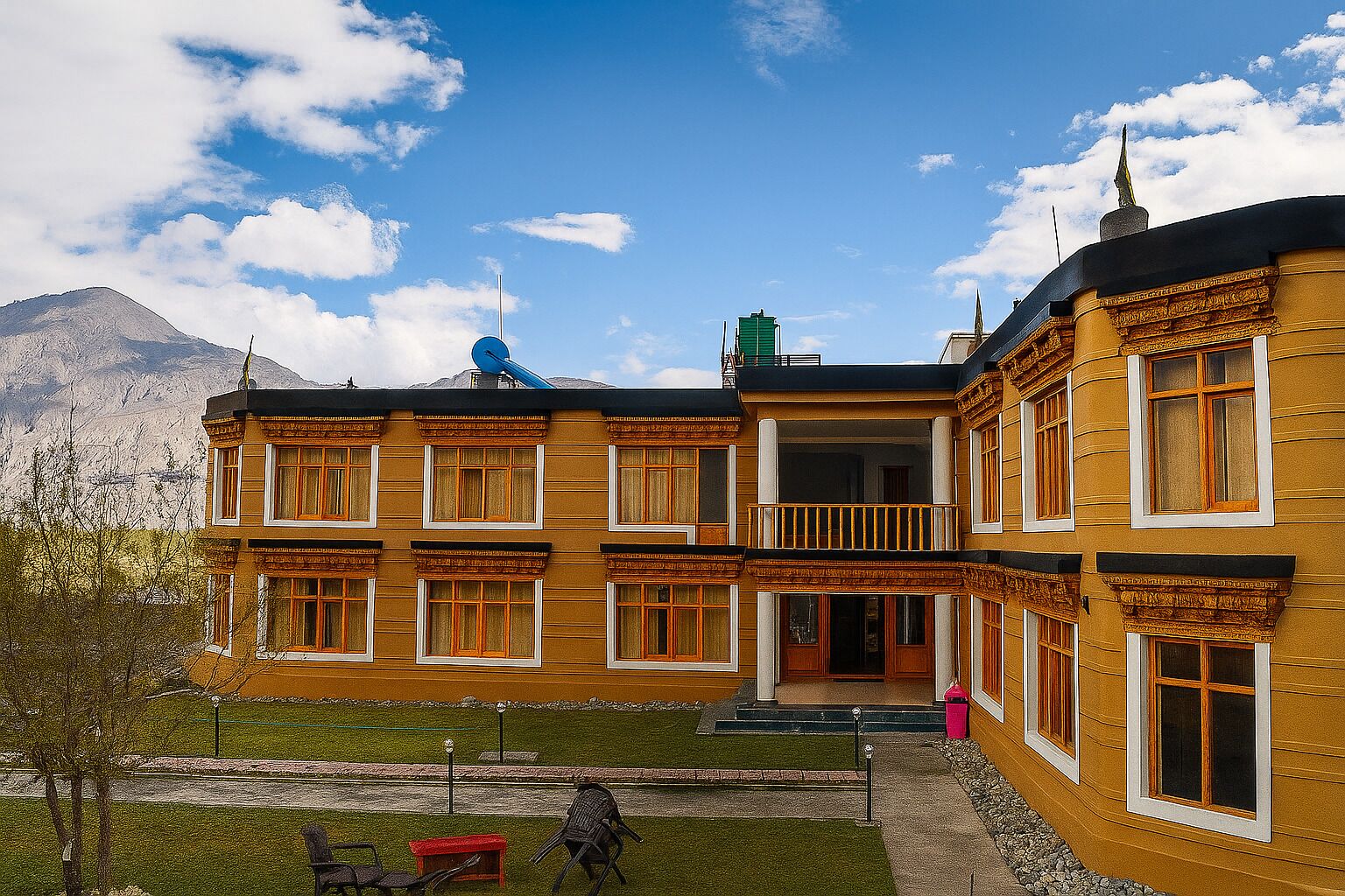 A two-story building with a balcony, a satellite dish, and a mountain in the background.