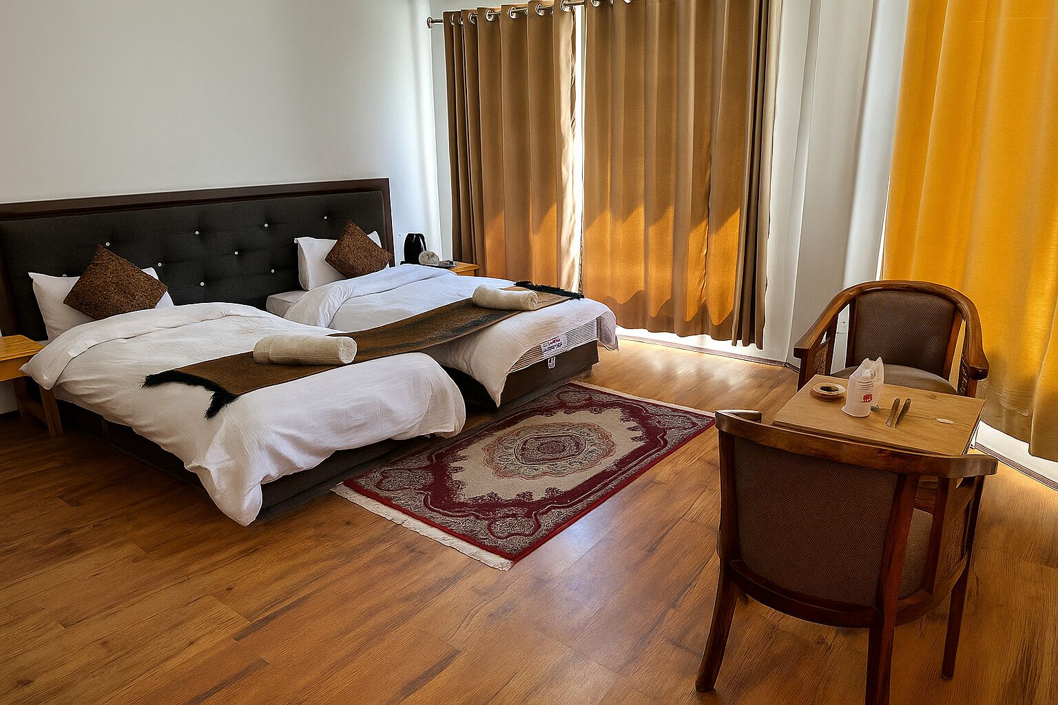 A double bed with a dark headboard, a wooden side table with a cup and a tissue, and a chair with a cushion.