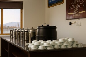 A kitchen counter with stainless steel containers, a large black pot, and white cups arranged on it.