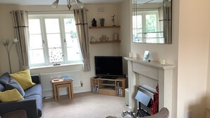 A living room with a sofa, armchairs, a TV, a fireplace, and a bookshelf.
