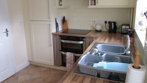 A compact kitchen with a built-in oven, a sink with a drying rack, and a toaster.