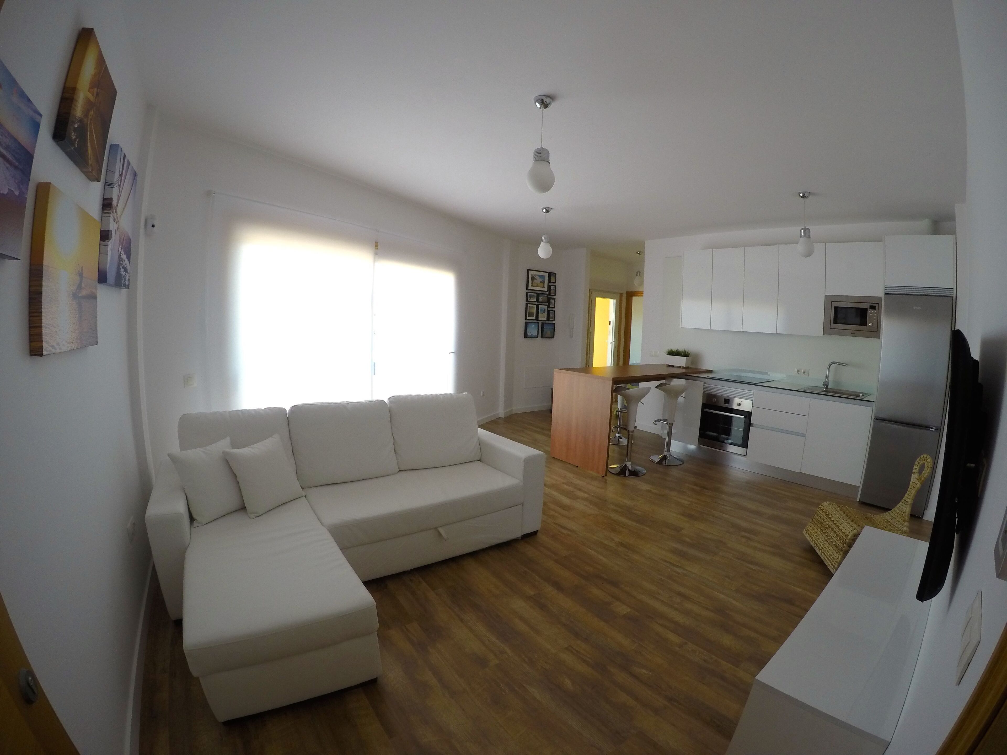 A modern apartment with a living room, kitchenette, and a dining area.