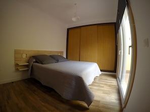 Una camera da letto con un letto, una testiera in legno e un'ampia finestra.